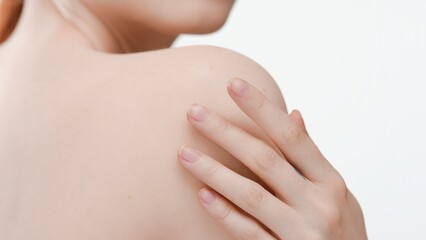 Close-up shot of young woman with perfect skin touches her shoulder on white background | Body care concept