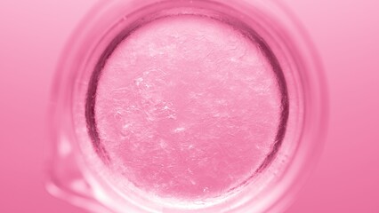 Obraz na płótnie Canvas Top view macro shot of glycerin being poured into beaker with water creating solution on pink background | Abstract body care cosmetics formulation concept