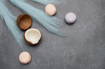 Tropical summer background with coconuts, marshmallows and blue feathers on a gray stone background. A holiday card with a place for text.