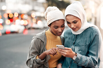 Check the maps. Cropped shot of two attractive young women wearing headscarves and standing...