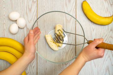 Woman hands mashing up several bananas to bake into bread,cupcakes. chef preparing ingredients for making cottage cheese, muffins,casserole at home kitchen cuisine, online cooking, recipe instruction