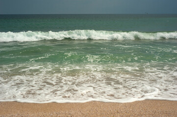 Crystal clear emerald green sea with gold sandy beach. Beach sea area. Natural beautiful landscape view of a tropical beach and green sea on a sunny weather.