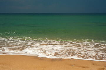 Crystal clear emerald green sea with gold sandy beach. Beach sea area. Natural beautiful landscape view of a tropical beach and green sea on a sunny weather.