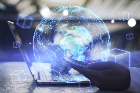 Close up of businessman hand using laptop keyboard and smartphone with reative glowing blue globe metaverse on blurry background. Augmented reality and future concept. Double exposure.