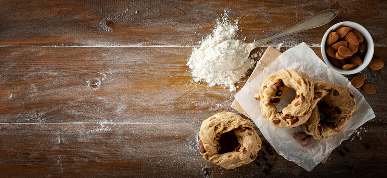Neapolitan taralli, lard, pepper and almonds on wooden pastry board, top view, space for text.