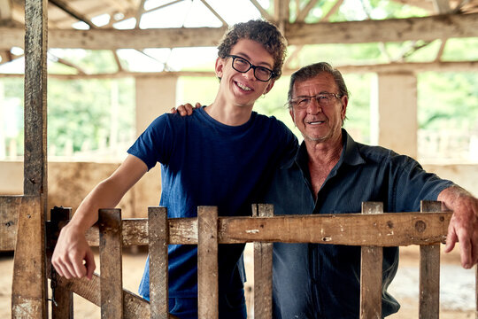 Hes falling into his fathers footsteps. Portrait of a farmer and his son inside a barn.