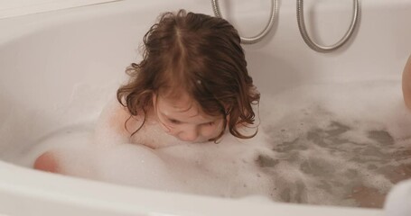 The twin girls take a bath in the evening, playing on their own.