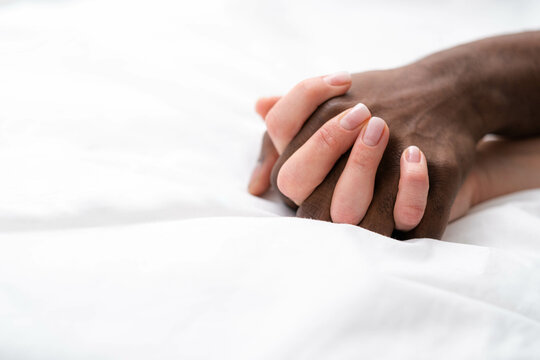 Hands close up multiracial couple african man and caucasian woman romantically touch each other on bed, lovers making Passion love