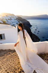 Young girl with long hair in white dress on Santorini island. Dawn. Sunrise.