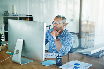 You can always find him at his desk. Cropped shot of a handsome young businessman working in his...