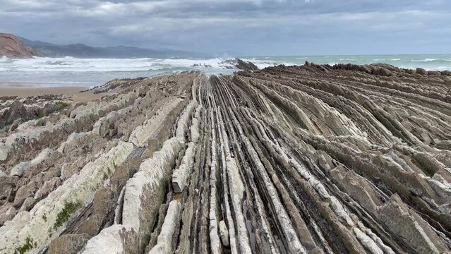 Sharp limestone rock layers in Zumaia beach on cloudy day. Popular flysch landmark from Game of Thrones TV set location in the Basque Country