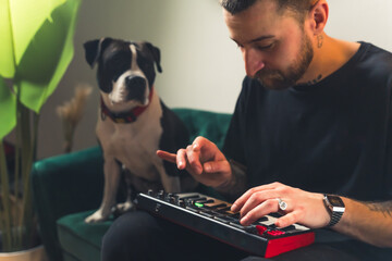 European male musician dj creating music on his sofa with his dog on the side. Creativity concept....