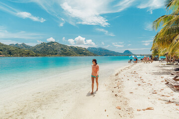 French Polynesia Travel beach picnic motu tour on Huahine, Tahiti, French Polynesia. Happy tourist woman walking on perfect beach living healthy lifestyle