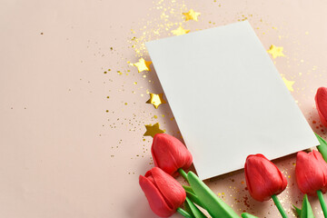 Banner with a blank sheet of paper, tulips and gold stars with sequins on a beige background. A place to copy. Flat position, top view