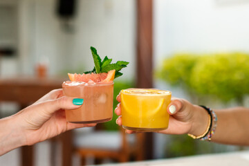 Two unrecognizable people toasting with tropical drinks