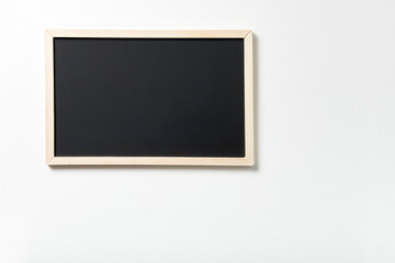 Blank chalkboard on a white wall. Concepts: school, education, training