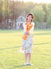 Portrait of elegant Chinese girl in dress enjoy carefree time with a bunch of flowers in her arms in forest park in sunny day. Outdoor fashion portrait of glamour young Chinese cheerful stylish woman