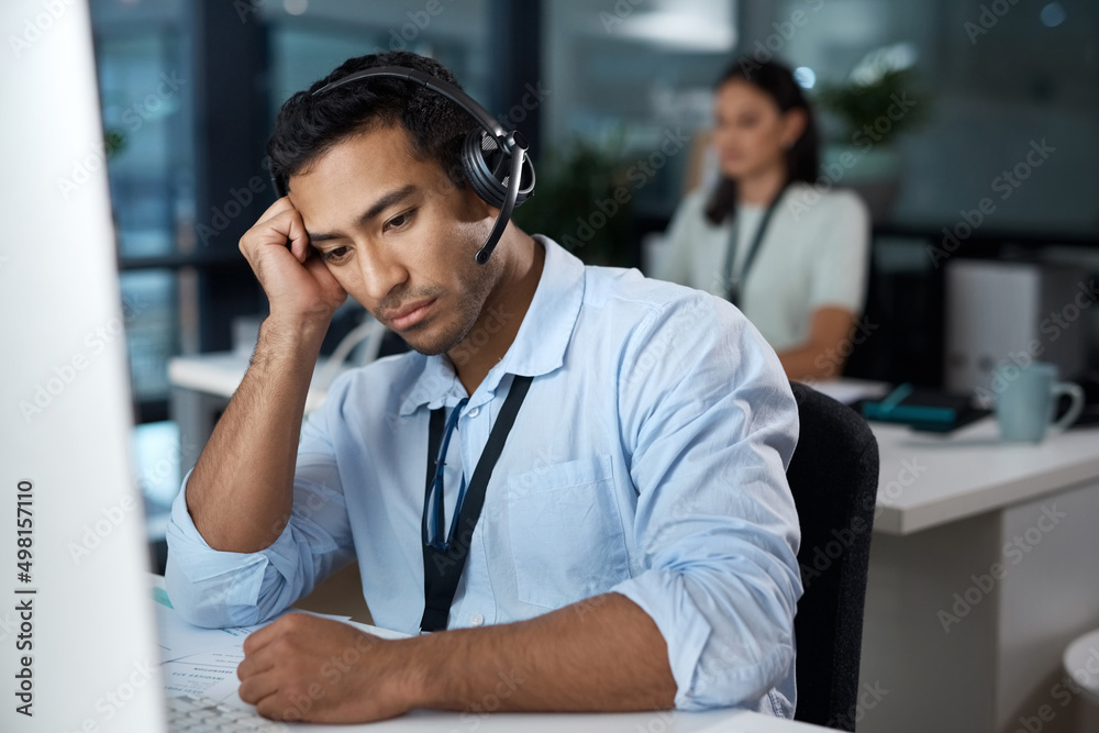 Poster i need support too. shot of a young man using a headset and looking depressed in a modern office.