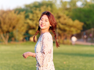 Portrait of elegant Chinese girl in dress enjoy carefree time in forest park in sunny day. Outdoor fashion portrait of glamour young Chinese cheerful stylish woman.