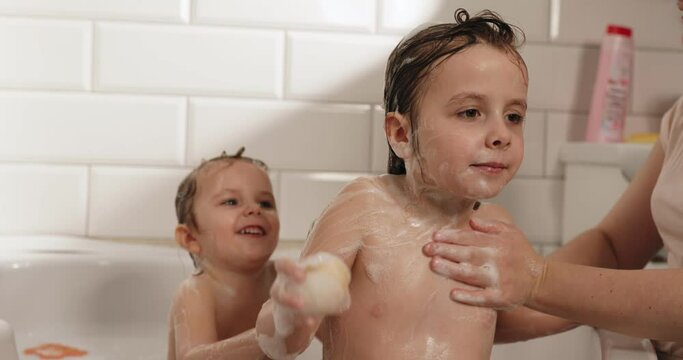 Mom washes the kids with natural soap in the bathroom. Soap that is safe for children.
