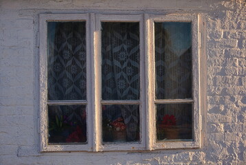 Fototapeta na wymiar window of the old house and a wall of white brick 