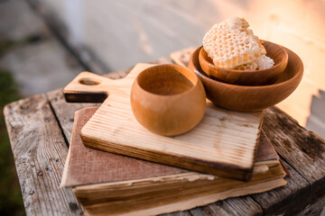 Wooden dishes with environmentally friendly honey on a cutting board near a book with old recipes for alternative medicine medicines or cosmetics