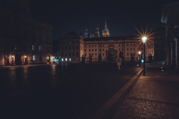 view of street lights and tiled streets and in the background prague castle at night in the center of the old town of prague
