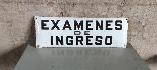 White sign with black letters announcing an exam