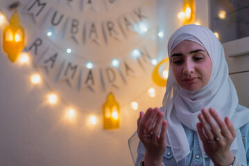 Muslim woman praying with hands up during the holy month Ramadan.