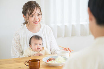 Obraz na płótnie Canvas 食卓で赤ちゃんと一緒にご飯を食べるママさん　笑顔　右にコピースペースあり