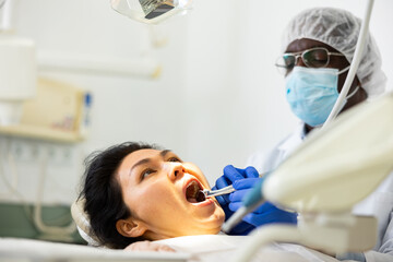 Portrait of Asian female patient during dental treatment in modern dentist office. Health care and oral hygiene concept..