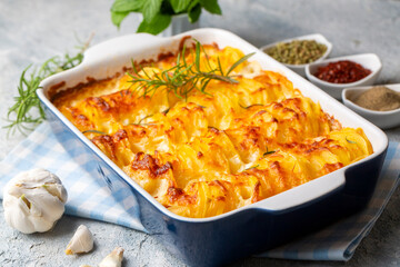 Potato gratin - graten (baked potatoes with cream and cheese) with rosemary and forks (Turkish name; Kremali patates)