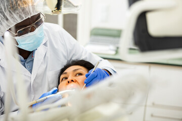 Adult Asian woman receiving professional teeth treatment in modern dental office ..