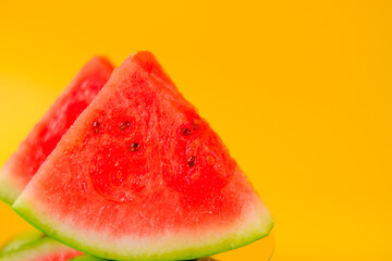 Watermelon. Ripe watermelon in a cut. Slices of watermelon on a bright yellow background. Appetizing fruits. 