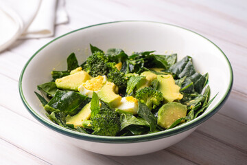 Avocado salad with broccoli, boiled egg in white vintage bowl on light salad