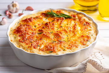 Potato gratin - graten (baked potatoes with cream and cheese) with rosemary and forks (Turkish name; Kremali patates)