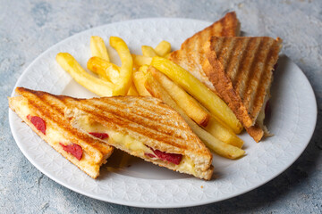 Turkish toast, mixed toast with cheddar cheese, sausage and ham, with fried potatoes (Turkish name; Karisik tost)