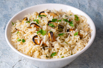 Mussel rice pilaf. Rice with mussels on small white plate on ceramic. (Turkish name; midyeli pilav)