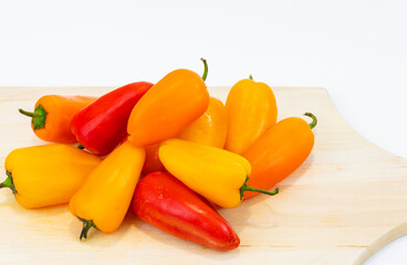 Fresh Red, Yellow and Orange Pepper on a White wooden Board.
