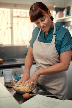 Getting Your Hands Dirty Is Apart Of The Recipe. Shot Of An Attractive Young Woman Reading A Recipe From A Book While Baking At Home.