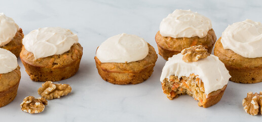 Banner of carrot cake muffins with a bite out of the one in front.