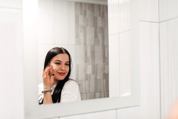 Skin care. Close up of young woman touching her face to apply moisturizer. White background