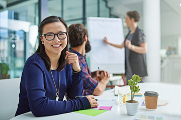Never lose sight of your ambitions. Portrait of a young businesswoman sitting in a meeting with colleagues in the background.