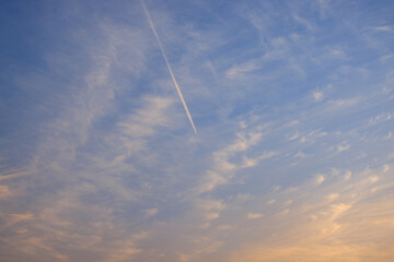 Distant passenger airplane streaks towards sunset glow