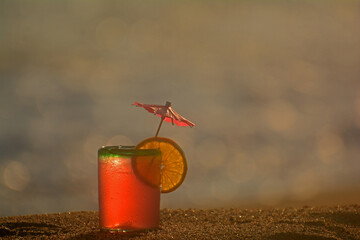 Tropical party drink in squat glass with party umbrella and lime slice on top on dark grainy...