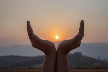 Fototapeta na wymiar Silhouette female hands holding sun on mountain