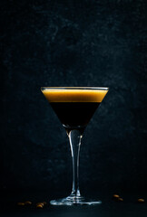 Classic alcoholic cocktail Espresso martini with vodka, coffee liqueur, syrup and ice in glass on dark counter background,  bar tools, negative space