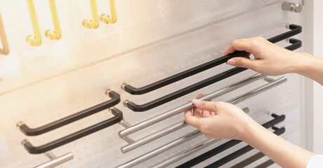 Female hand choosing the stainless handing door, the part of the door for the interior home, and renovating the house. For renovation concept.