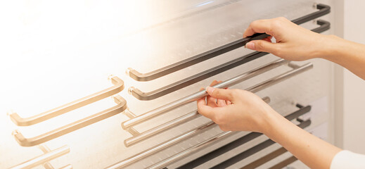 Female hand choosing the stainless handing door, the part of the door for the interior home, and renovating the house. For renovation concept.