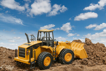Wheel loader are digging the soil in the construction site on the clouds and sky background .